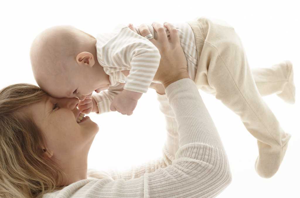 Mother holding up baby girl (3-6 months) smiling 74951778