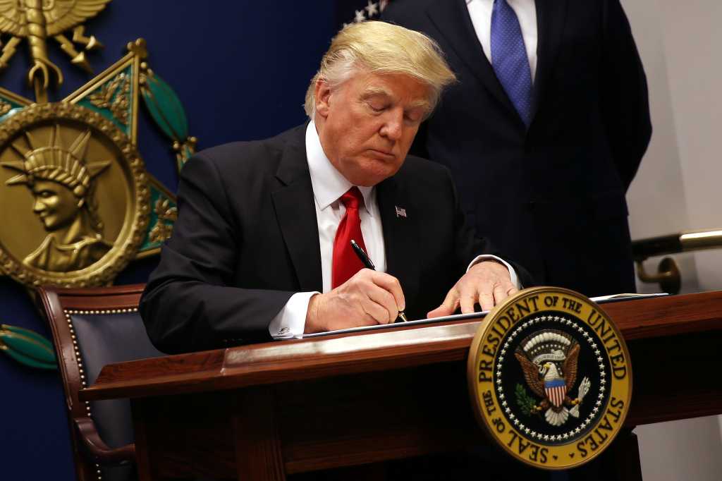 President Donald Trump signs an executive order to impose tighter vetting