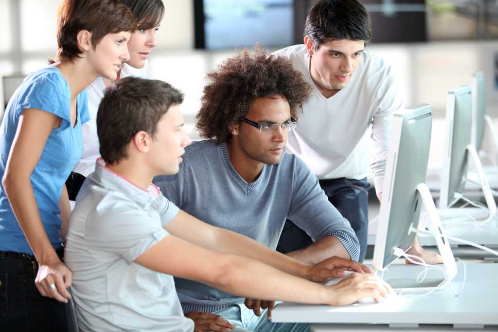 group of millennials working together looking at computer