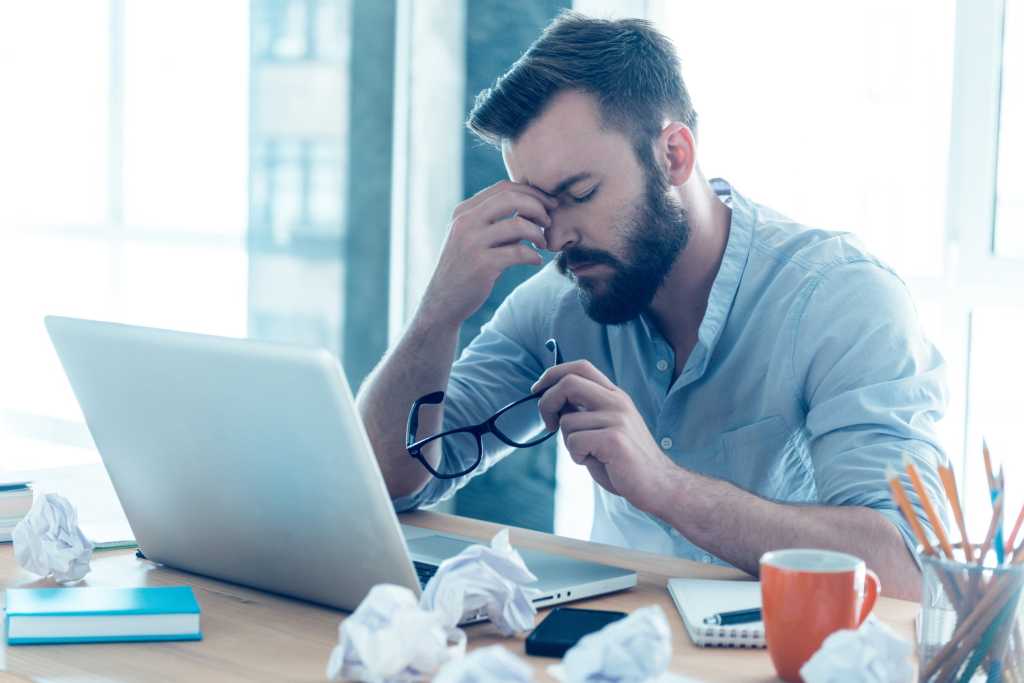 Man sitting at laptop looking tired