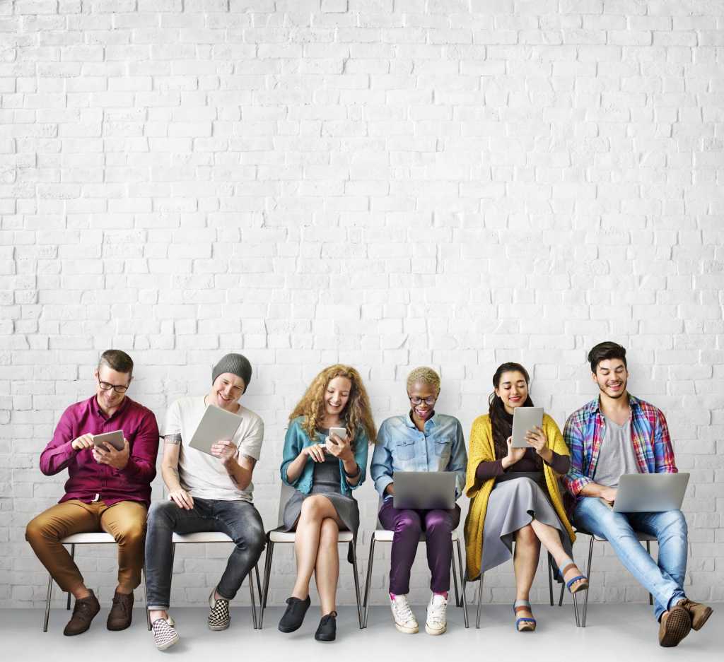 Group of millennials sitting with mobile devices in a row