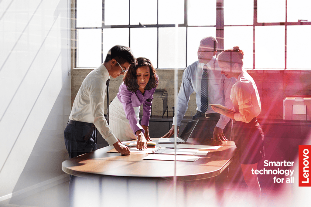 Image of business people stood around a table in a meeting room talking to each other