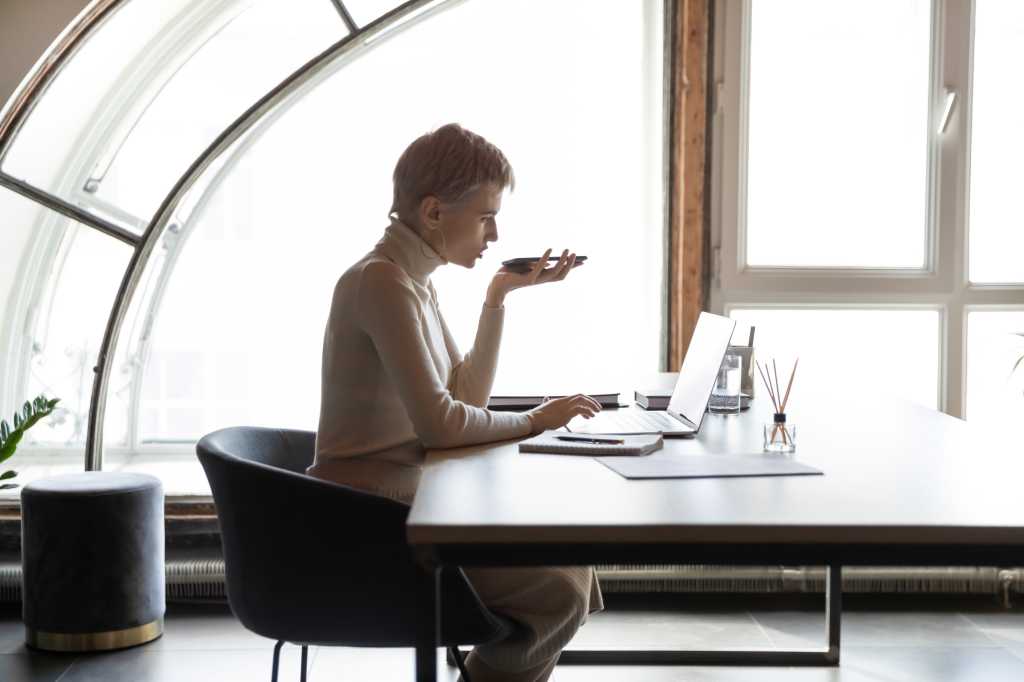 female employee sit at desk in modern office work online on laptop talk